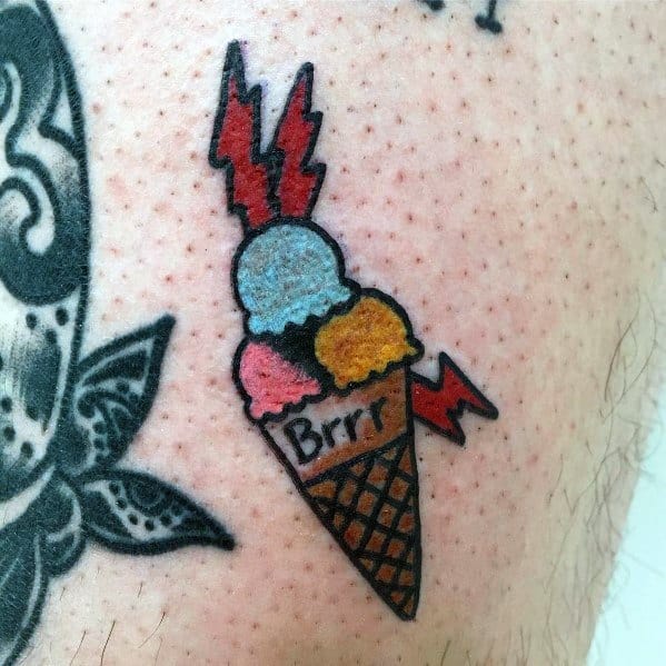 Tattoo of a small ice cream cone with three colorful scoops, lightning bolts, and the word "Brrr," blending playful and bold traditional elements.