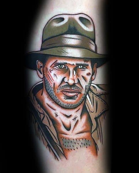 Bold and detailed tattoo of Indiana Jones, featuring his iconic fedora, rugged expression, and battle-worn look in a comic book-style design.