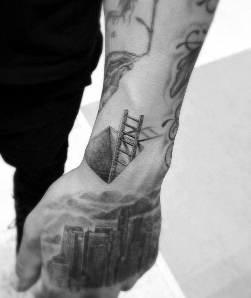 Small, detailed ladder tattoo emerging from a cube, symbolizing breaking barriers, ideal for men's hand or wrist placement.