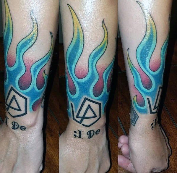 Vibrant tattoo featuring Linkin Park’s hexagon logo with blue, yellow, and red flames, wrapping around the lower leg.