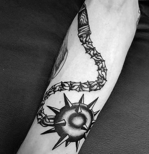 Black and gray mace tattoo featuring a spiked ball on a barbed chain with a wrapped handle, symbolizing strength, power, and resilience.