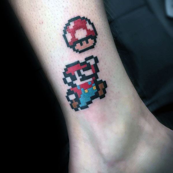 Retro *Super Mario* tattoo featuring an 8-bit pixel design of Mario jumping for a Super Mushroom, capturing classic gaming nostalgia in bold colors.