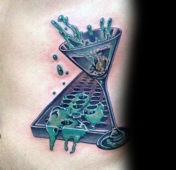 Realistic martini glass tattoo with a green liquid splash effect, placed on a bar mat. A bold and dynamic design with vibrant colors and reflections.