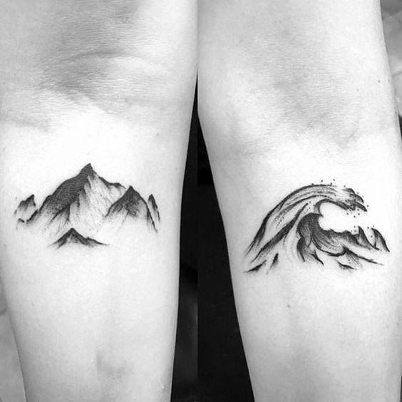 Minimalist wrist tattoos featuring a shaded mountain on one side and a crashing wave on the other, symbolizing balance and nature’s contrast.