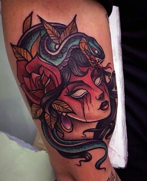 Neo-traditional tattoo of a mysterious woman with a blue snake coiled around her head, bold red face paint, and detailed floral accents.