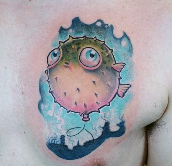 Whimsical pufferfish tattoo with soft shading, expressive eyes, and a balloon-like string, surrounded by watercolor-style ocean waves.