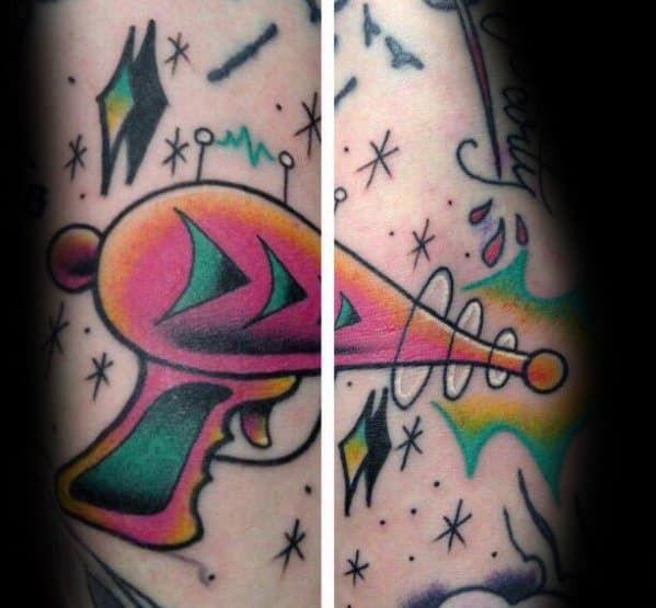 Vibrant retro ray gun tattoo with a bold pink and yellow color scheme, futuristic energy blast, and space-themed background details.