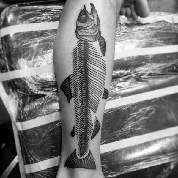 Black and grey tattoo of a salmon skeleton with bold linework and intricate shading, placed on the leg for a striking and symbolic design.