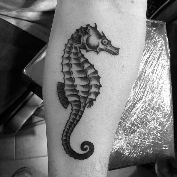 Black and grey seahorse tattoo on forearm, featuring bold shading and fine details for a classic and realistic marine-inspired design.