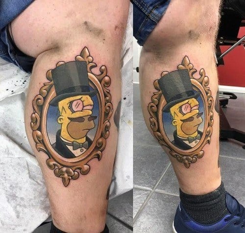 Elegant tattoo of Homer Simpson in a top hat and monocle, framed in an ornate vintage-style portrait design on the leg.