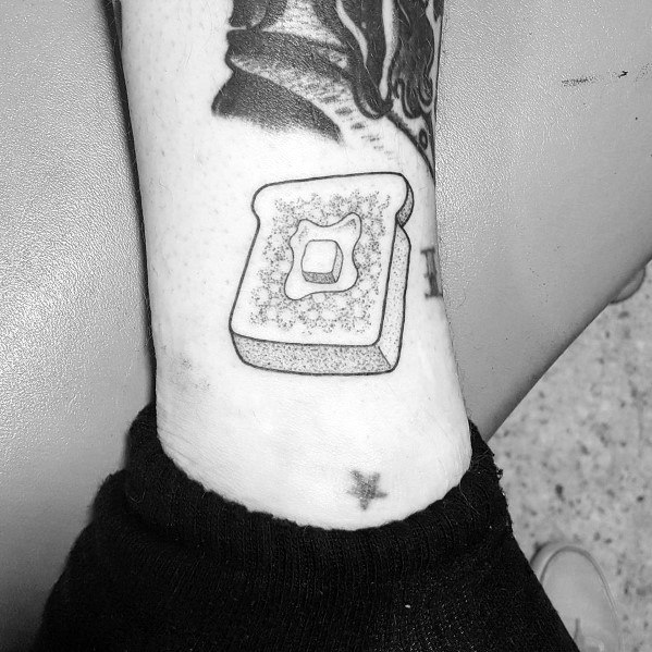 Minimalist toast tattoo with a square butter pat, inked in fine black lines with stippling for texture, creating a simple yet detailed design.