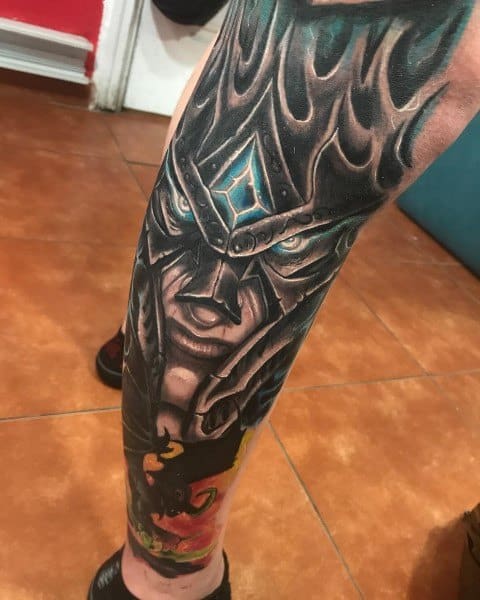 Realistic tattoo of the Lich King from World of Warcraft, featuring his iconic helmet, glowing blue gem, and intense gaze, inked as a full leg sleeve.