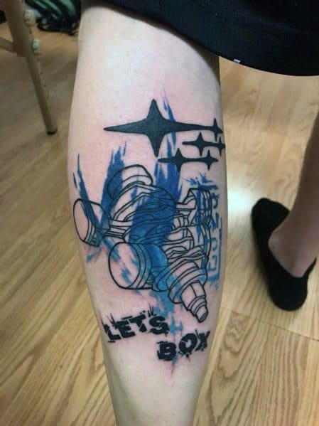Blue and black Subaru-themed tattoo featuring a detailed boxer engine, Subaru stars, and the phrase "LET'S BOX" in a bold, stylized design.