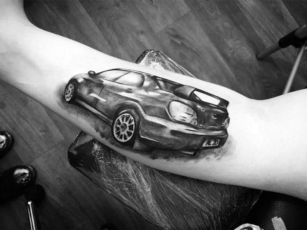 Realistic black and grey Subaru WRX STI tattoo on the inner arm, showcasing a detailed rear view with shading and depth for a dynamic effect.