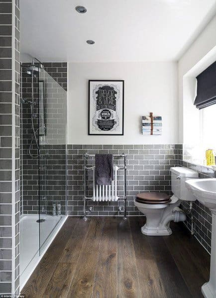 Modern bathroom with dark grey tiles, wood flooring, and a glass shower enclosure