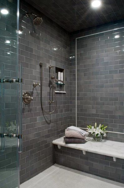 Grey beveled subway tile shower with marble bench, chrome fixtures, and recessed niche.