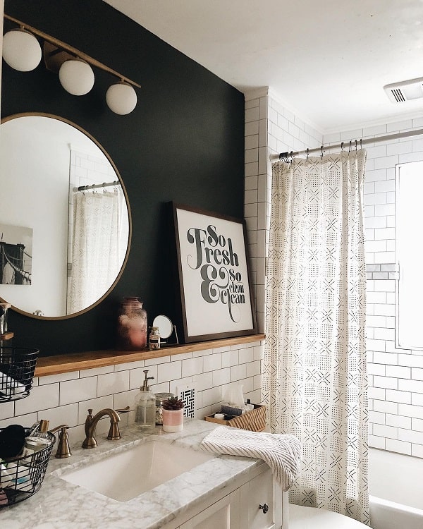 Rustic farmhouse bathroom with white subway tiles, round mirror, marble sink, and wall art.