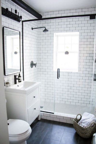 Modern bathroom with glass shower, white tiles, and sleek black fixtures