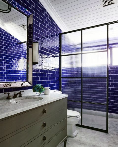 Glossy blue subway tile shower with black-framed glass divider.