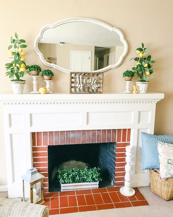brick fireplace with white mantel and small lemon trees