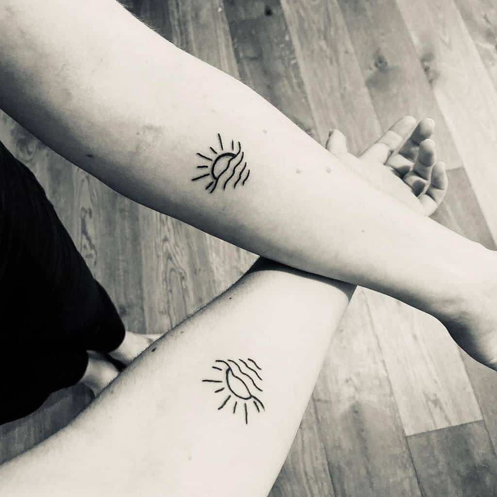 Matching minimalist sun tattoos, featuring a half-sun with rays and wavy lines, symbolizing warmth, connection, and unity