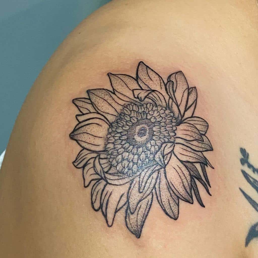 A stunning line art sunflower tattoo gracefully adorns the shoulder, capturing simplicity and elegance in its design