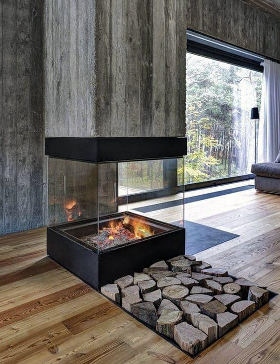 A modern fireplace with glass walls and sunken firewood storage, blending rustic charm with contemporary design.