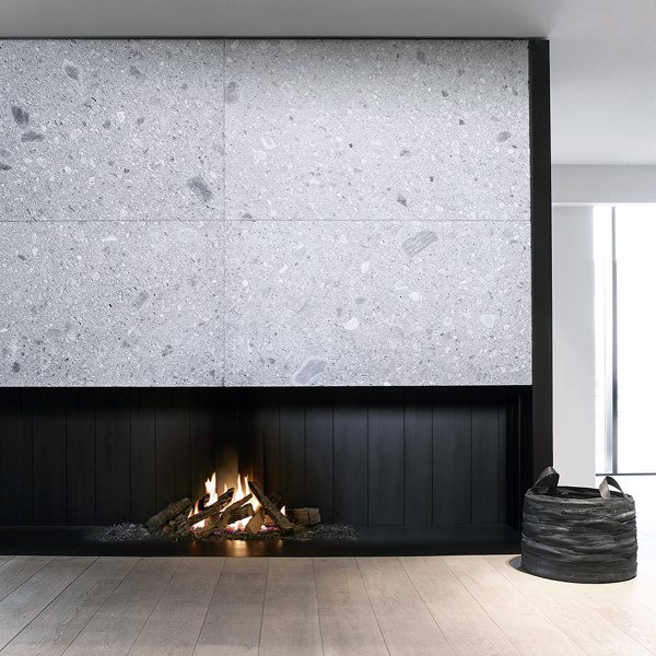 A contemporary sunken fireplace with black paneling and a light stone backdrop, blending minimalism with warmth.