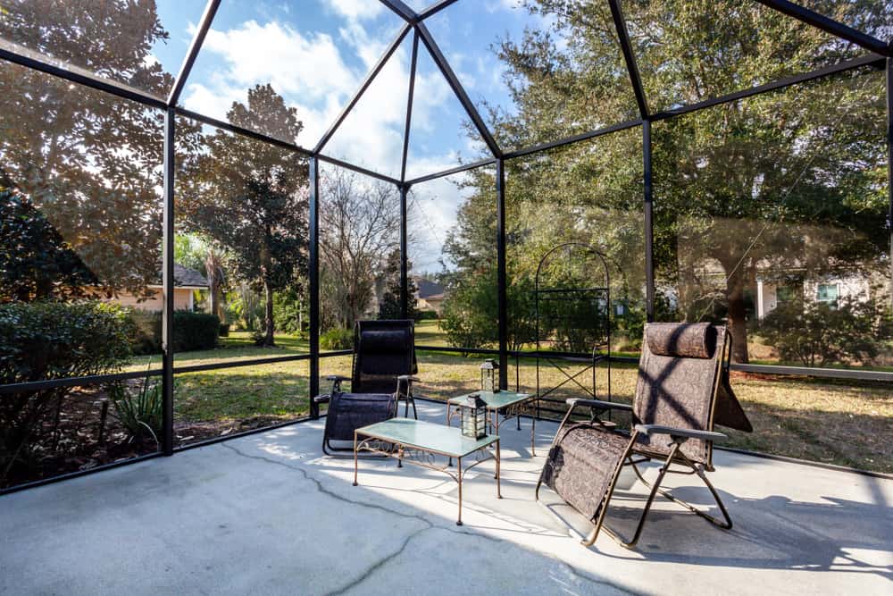 large window sunroom patio concrete floor two sun chairs glass table tops