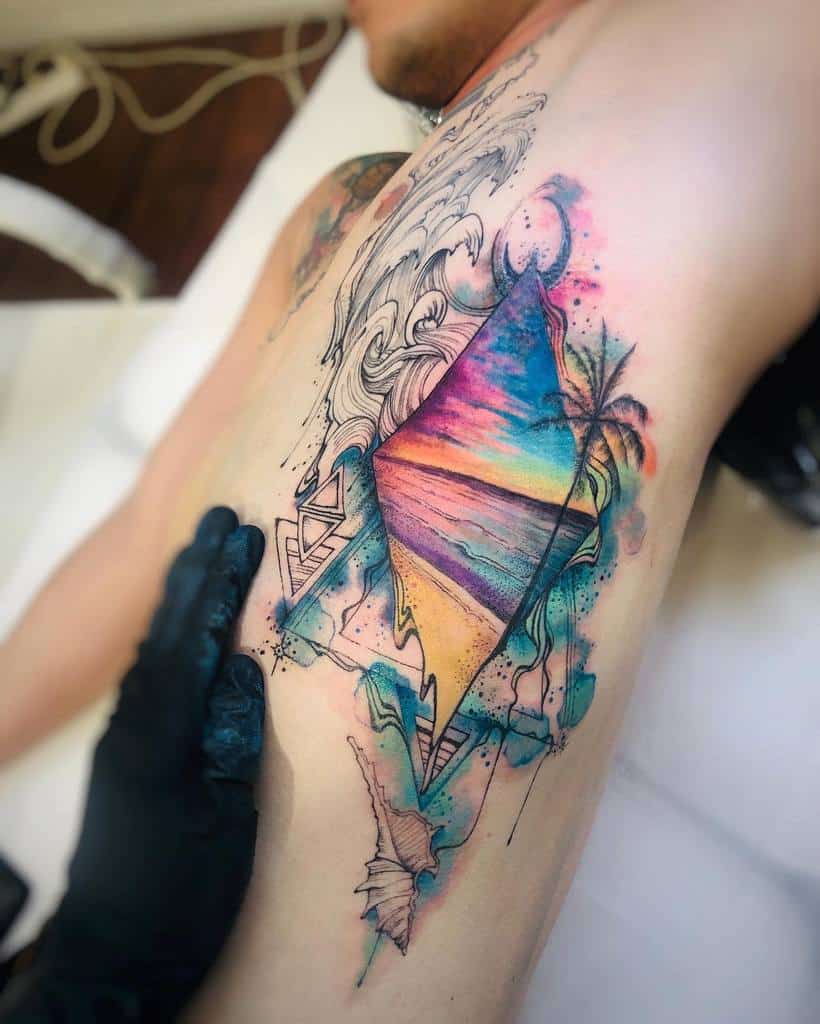 Vibrant watercolor-style tattoo featuring a geometric window revealing a tropical sunset over the ocean, surrounded by abstract waves, palm trees, and tribal-inspired patterns