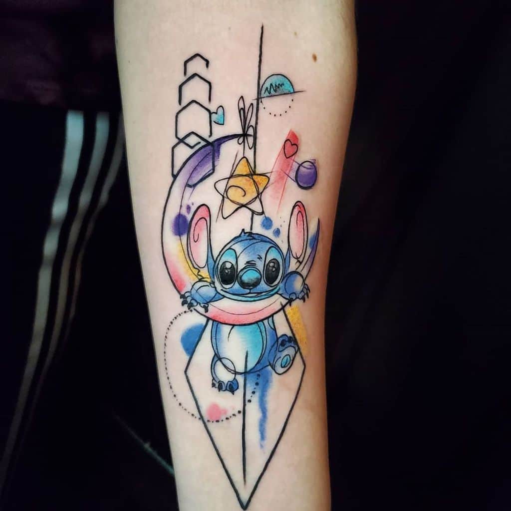 Colorful tattoo of Stitch from Lilo & Stitch surrounded by geometric shapes and watercolor splashes, on the forearm.