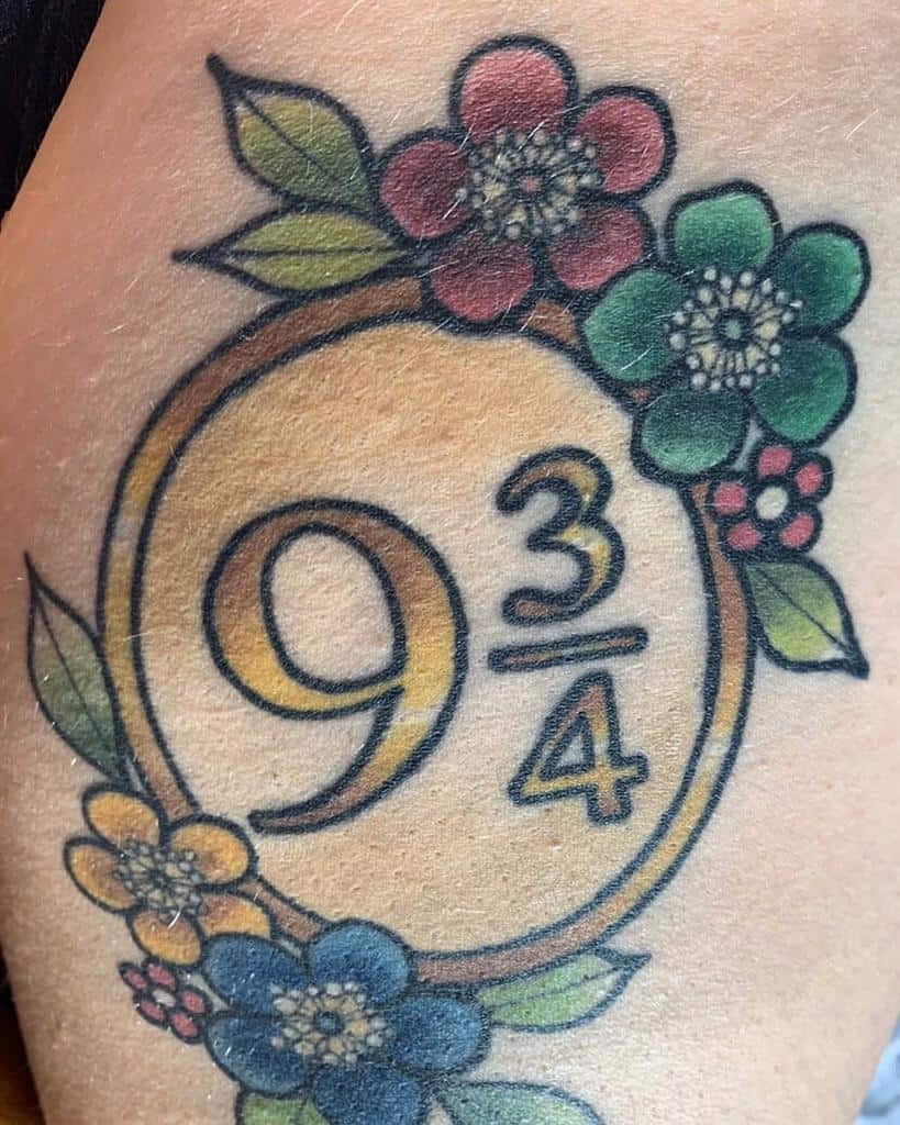 Colorful Harry Potter tattoo of Platform 9¾, framed with vibrant flowers and leaves