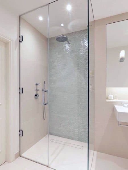 Minimalist bathroom with a corner glass shower enclosure, gray tile wall, and a white sink