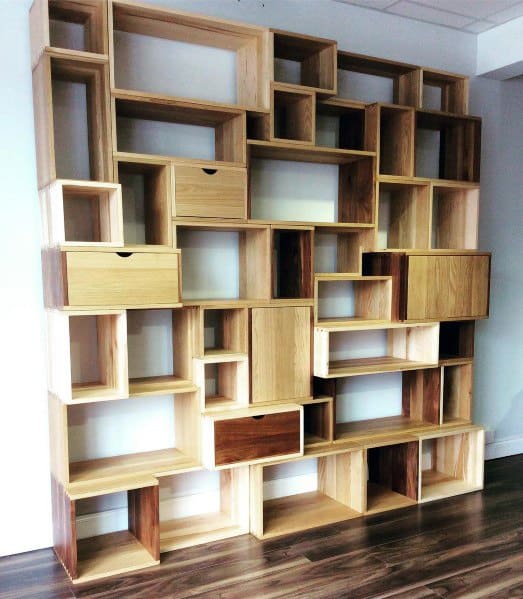 Bookshelf with irregularly arranged open cubbies and drawers on a wooden floor