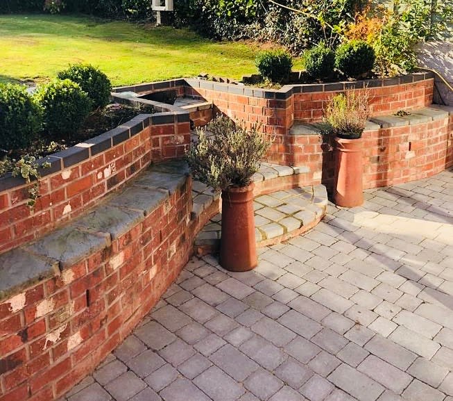 tired brick retaining wall paver patio small green shrubs