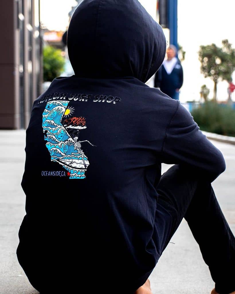 The back of someone wearing a surf shop logo hoodie