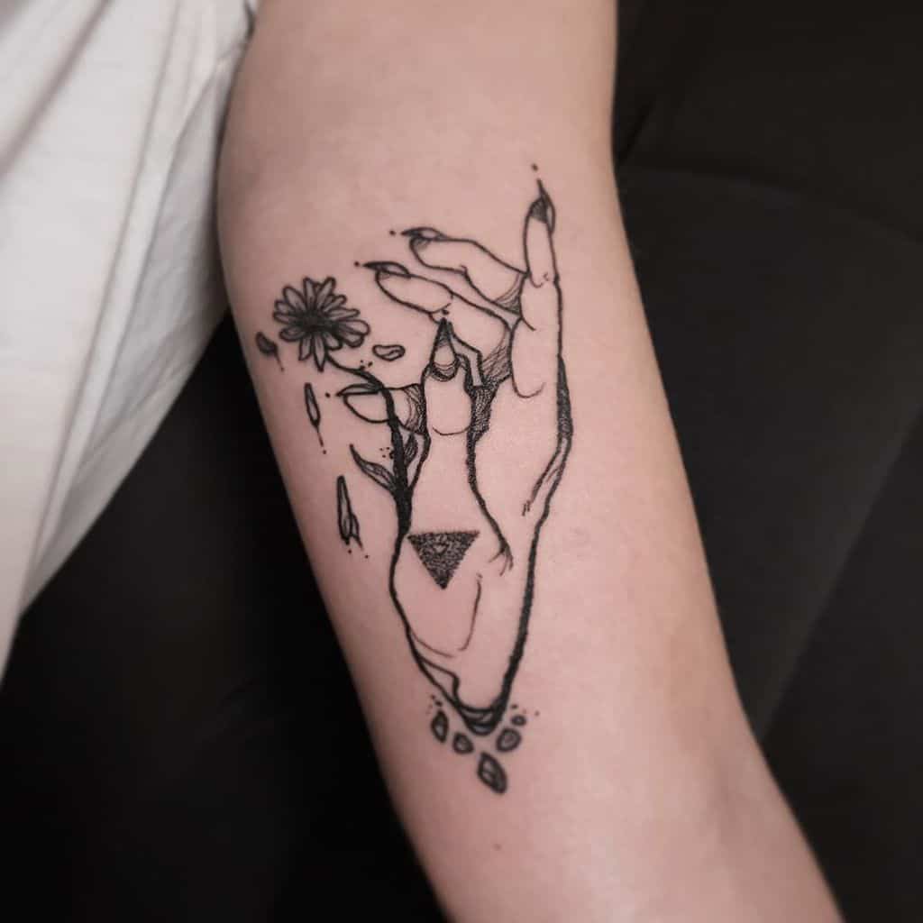 Bicep tattoo black and grey surreal witch hand daisy