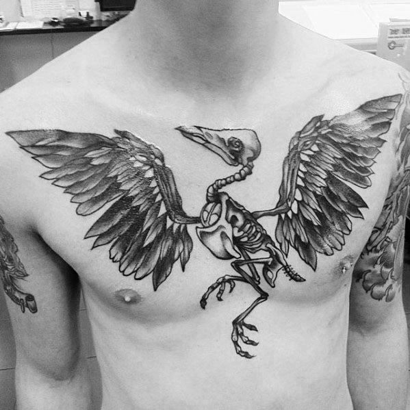 Chest tattoo of a skeletal bird with detailed wings spread across both sides, combining anatomical precision with bold, gothic style.