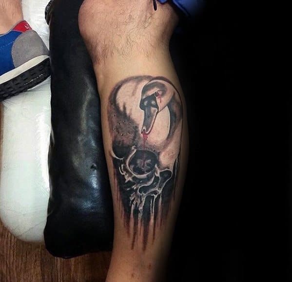 Dark surreal leg tattoo of a swan with a bleeding beak, hovering over a melting skull, blending elegance with macabre imagery.