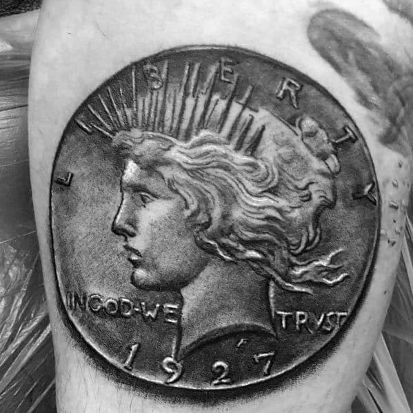 Realistic tattoo of a 1927 Peace Dollar coin, featuring intricate shading and fine details for a bold, three-dimensional effect.