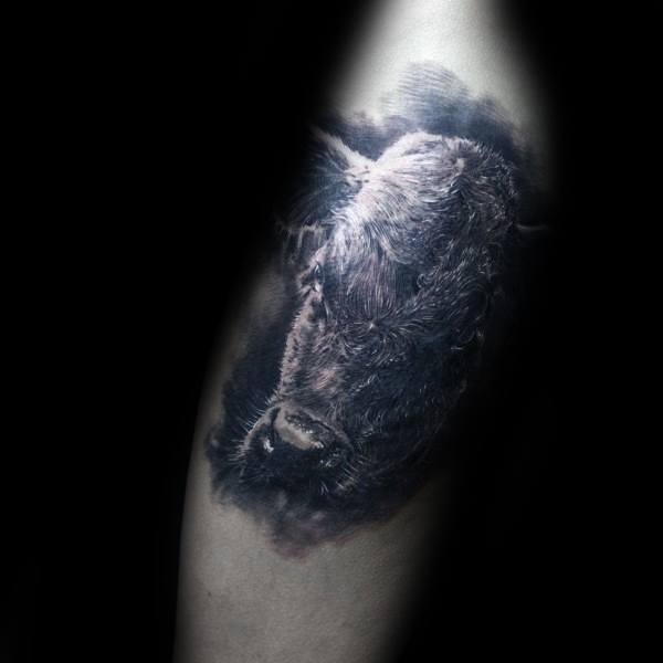Hyper-realistic tattoo of a cow’s head with deep texture and contrast, blending seamlessly into the skin for a lifelike 3D effect.