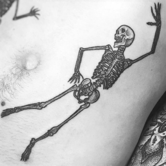 Dancing skeleton tattoo with a fluid pose and fine black ink details, creating a playful and dynamic design on the ribcage.