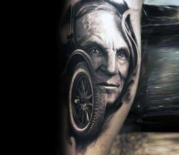 Realistic black and grey tattoo featuring Henry Ford’s portrait blended with a vintage Ford wheel, symbolizing automotive innovation and legacy.