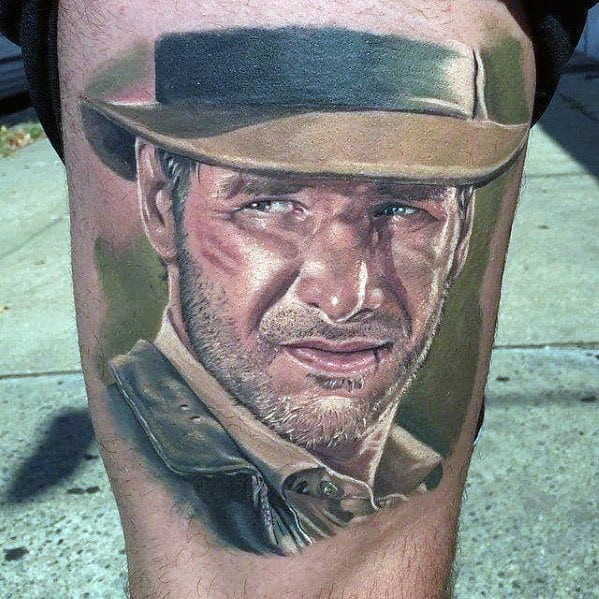 Hyper-realistic tattoo of Indiana Jones, capturing his intense gaze, rugged features, and iconic fedora with lifelike shading and detail.