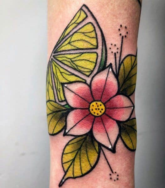Bold floral and lime tattoo with vibrant green and yellow citrus shading, complemented by a pink flower and stylized leaves for a fresh design.