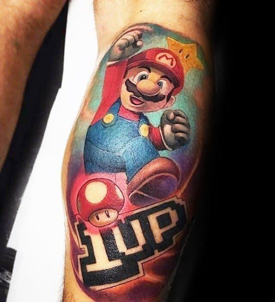 Vibrant *Super Mario* tattoo featuring Mario mid-jump with a Super Star, 1-Up text, and a Mushroom, blending bold colors and dynamic shading.