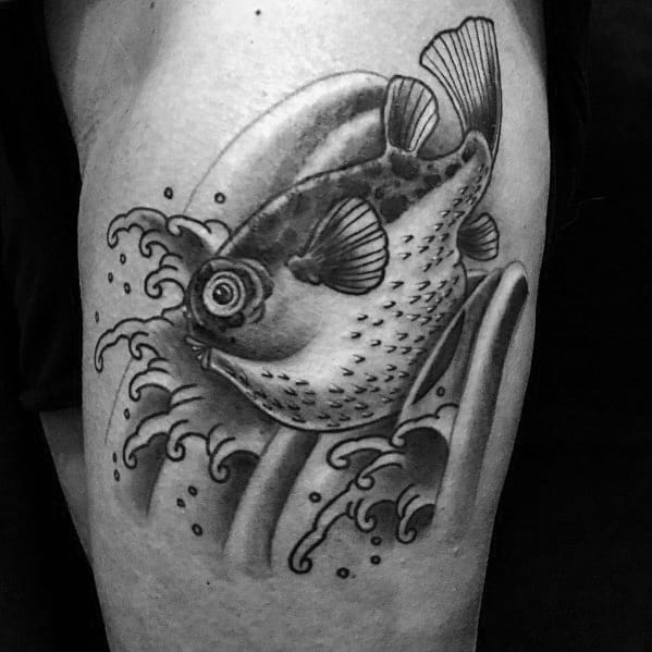 Black and grey pufferfish tattoo with realistic shading, dynamic waves, and flowing movement, creating a bold and detailed aquatic design.