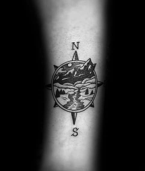 Compass tattoo with a scenic mountain landscape inside, symbolizing adventure, exploration, and a deep connection to nature.