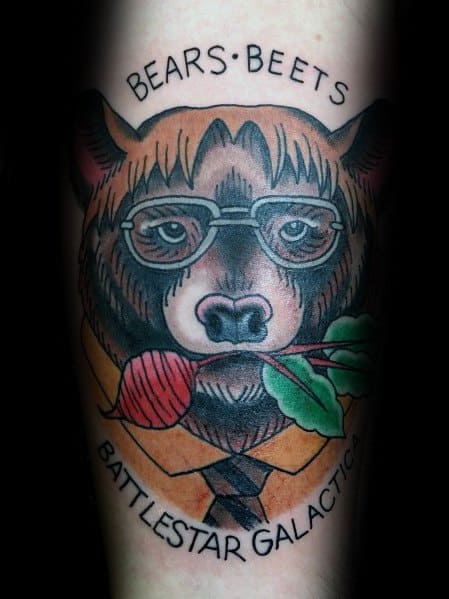Color tattoo of a bear wearing Dwight Schrute’s glasses and suit, holding a beet in its mouth, with "Bears. Beets. Battlestar Galactica." referencing Jim’s prank from *The Office*.