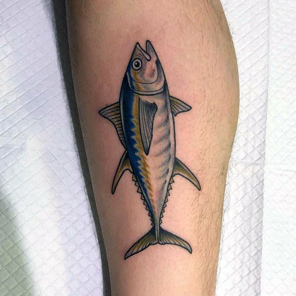 Realistic tuna fish tattoo on a man's leg, featuring smooth shading, fine details, and vibrant blue and gold tones for a lifelike design.